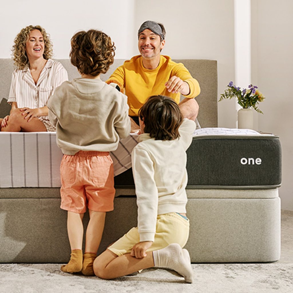 MaxColchón JustSleep One en un dormitorio con una familia junto al colchón