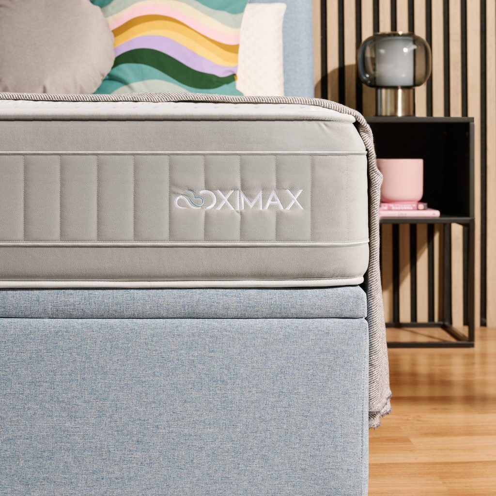 MaxColchón Oximax 2.0, lateral con el logotipo Oximax sobre un canapé