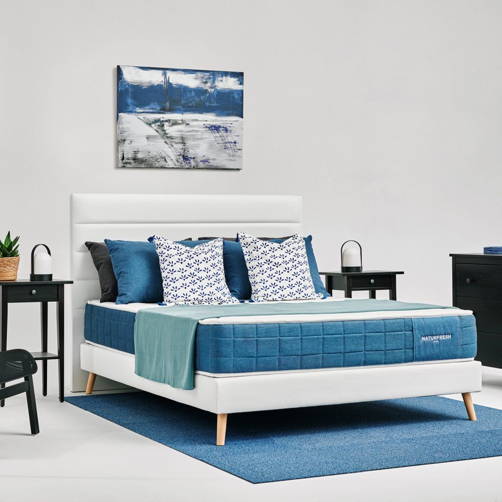 MaxColchón Naturfresh sobre una cama en un dormitorio con alfombra azul