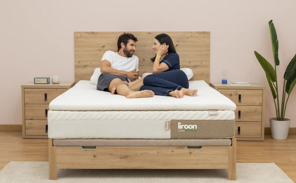 Pareja sentada en una cama con el Liroon Topper Látex