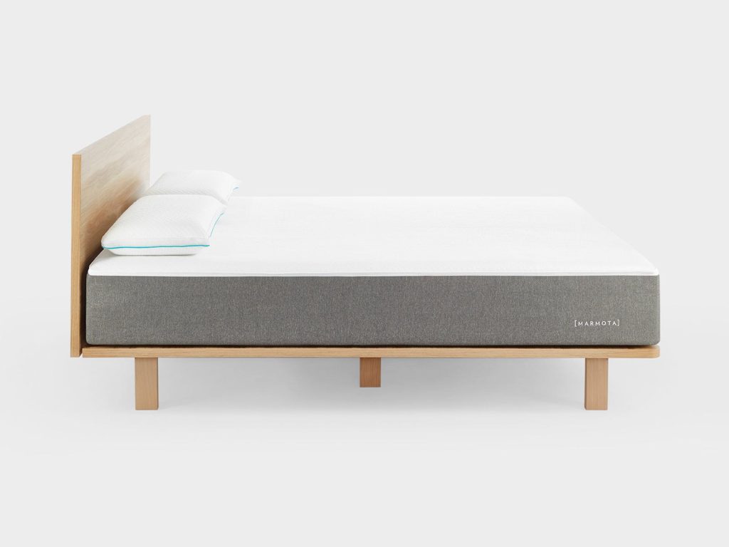 Marmota Hybrid Premium sobre una cama de madera con almohadas
