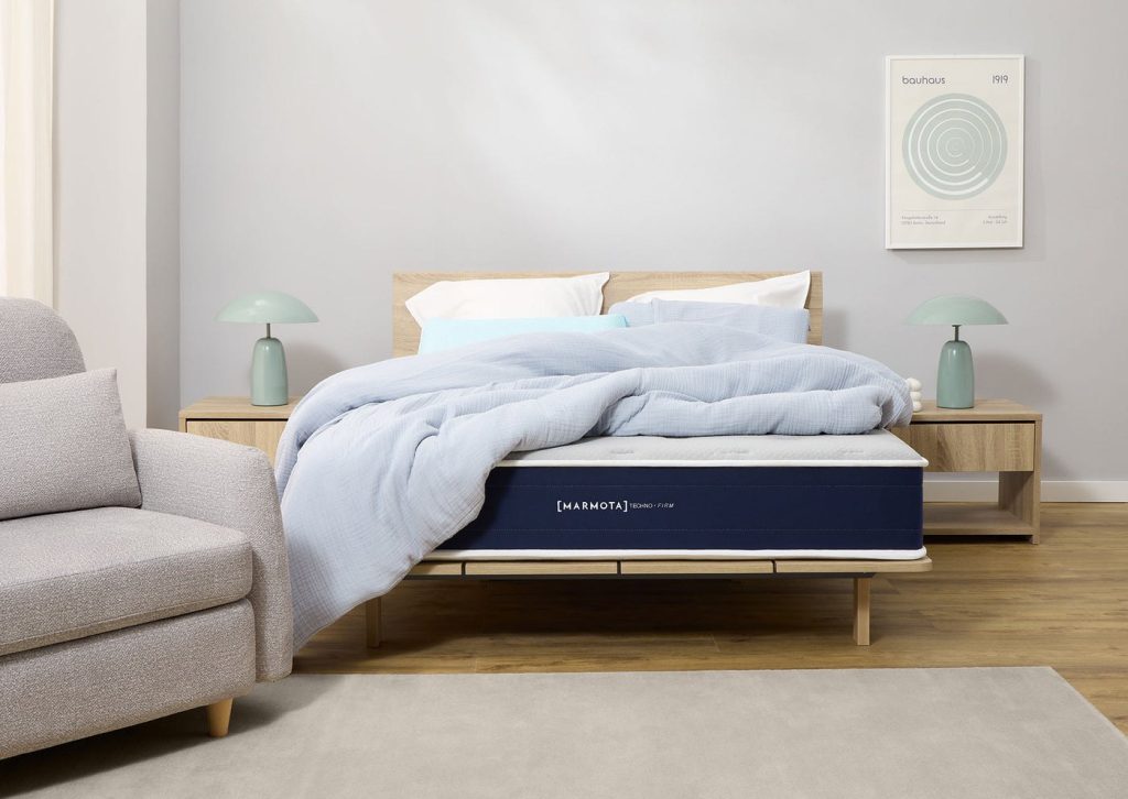 Marmota Hybrid Techno Firm con ropa de cama en un dormitorio