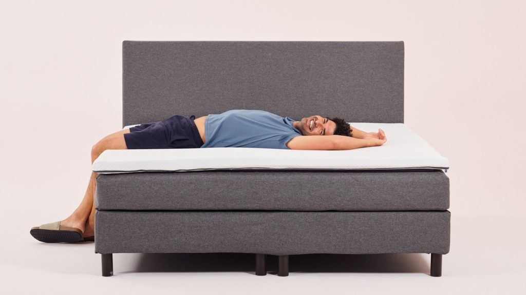 Topper Emma Original sobre una cama con un hombre tumbado boca arriba