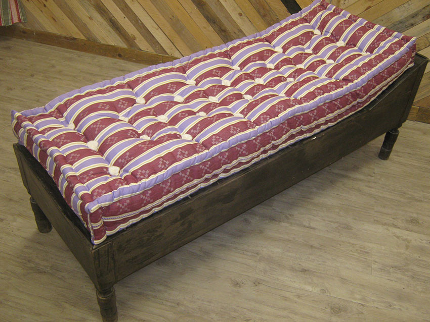 Altorricón Colchón de Lana Natural con tela de rayas rojas sobre una cama de madera