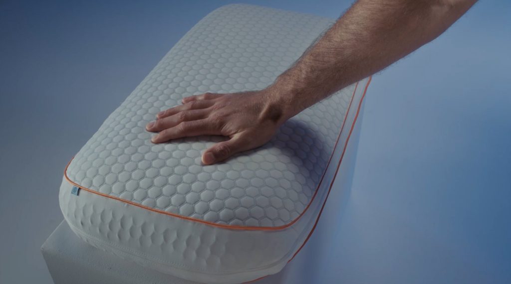 Mano sobre la funda hexagonal de la almohada Emma Performance Adapt