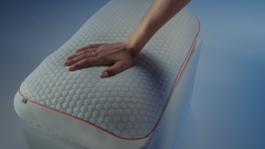 Mano presionando la funda de la almohada Emma Performance Hybrid