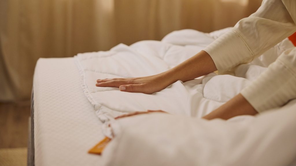 Mano sobre el acolchado del Edredón Emma extendido en la cama