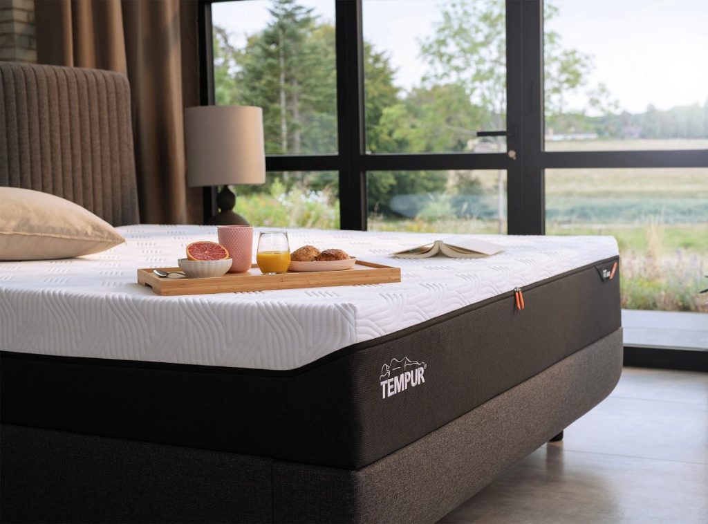 Tempur PRO con funda QuickRefresh blanca sobre una cama en un dormitorio con ventanal