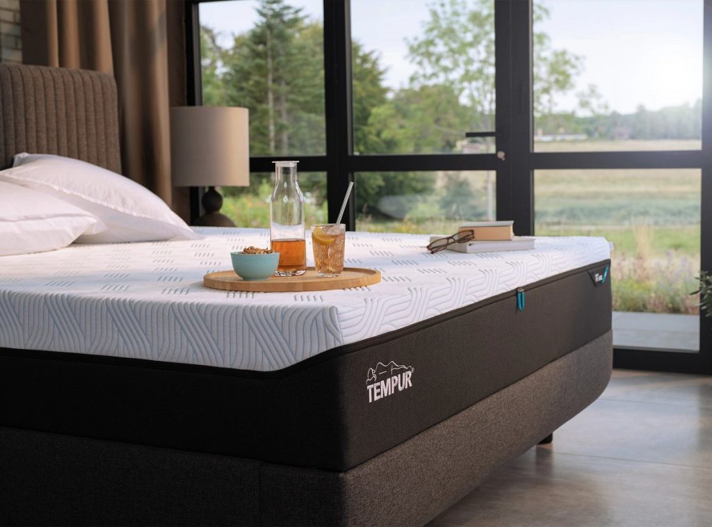 Tempur PRO Plus SmartCool con funda SmartCool sobre una cama en un dormitorio con ventanal